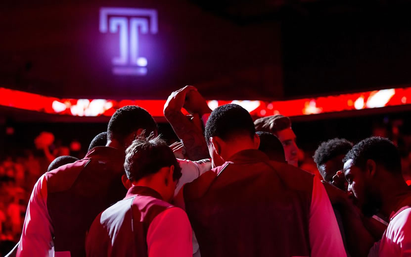 Temple Men's basketball player stand in huddle with arms raised