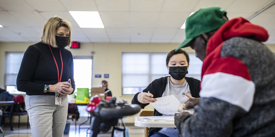 Students wearing masks work with a patient inside a classroom.