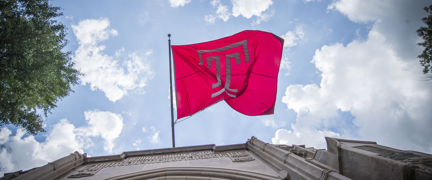 Temple T flag flying against a blue sky.