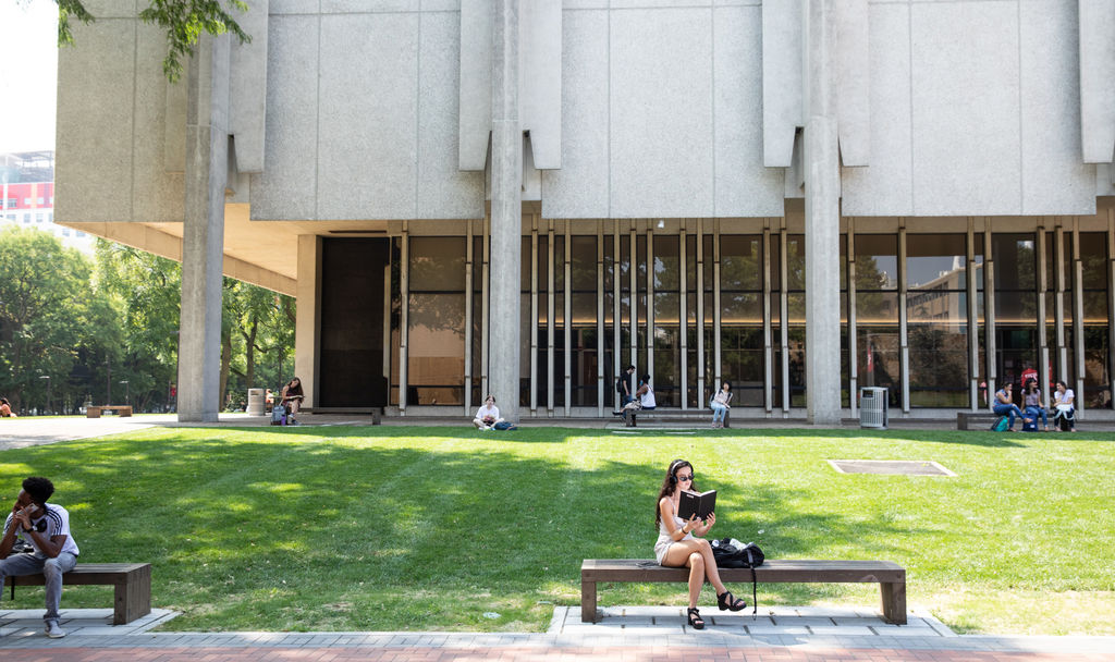 Temple University Female Student Readying On A Bench Listening To Music