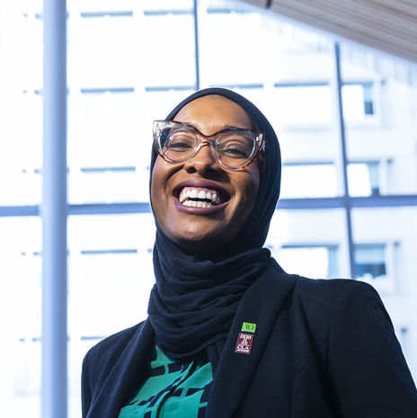 Erinn Corbett-Wright is smiling and posing in front of a glass window