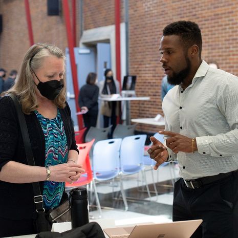 A masked woman talks with a man wearing a white shirt.