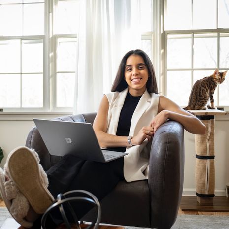 An image of Loymi Peralta Cruz smiling while sitting and holding her open laptop.