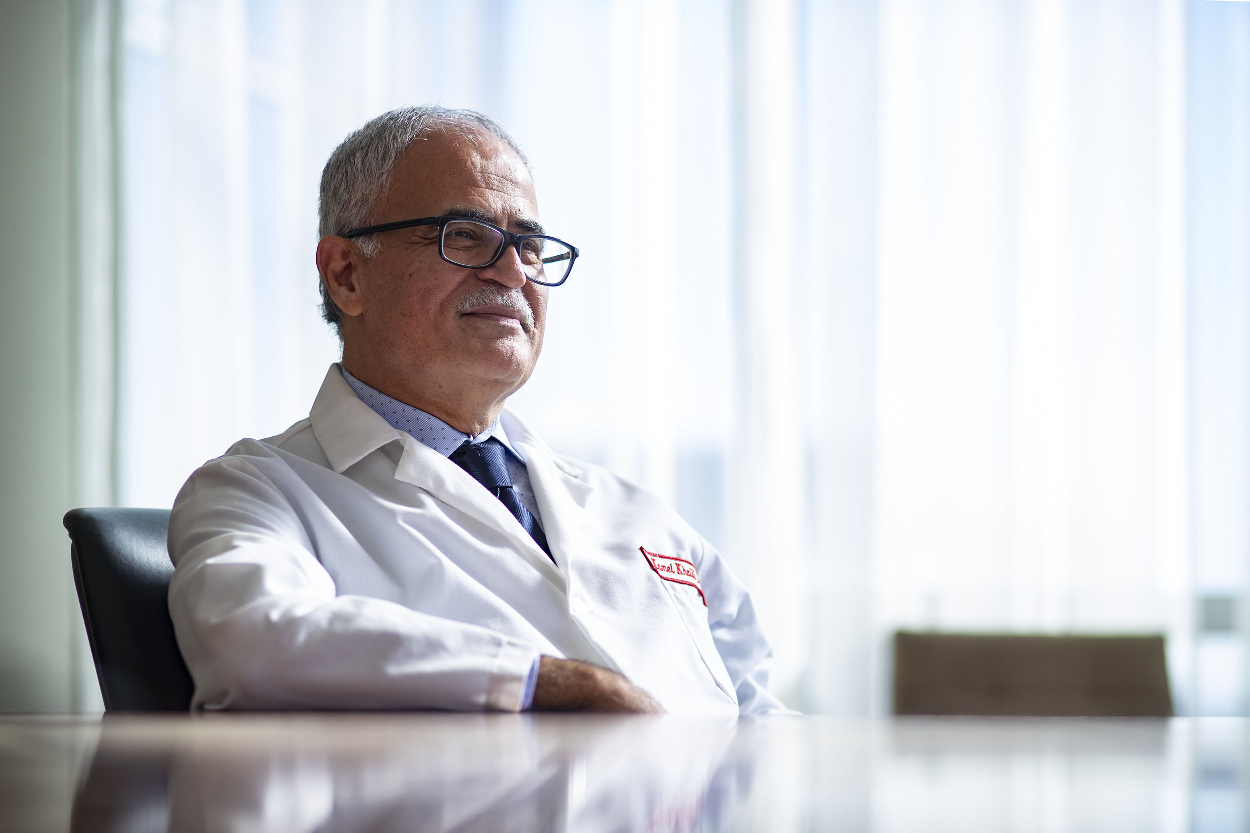 Dr. Kamel Khalili wearing a white lab coat and sitting at a table