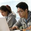 Two students work side by side on computers in a Temple classroom.
