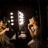 Two female students apply makeup backstage before a show.