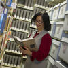 Woman standing in a library reading a book by author Audre Lorde.