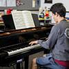 A male student plays a baby grand piano.