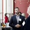 A male student wearing a blazer is in conversation during a professional event.