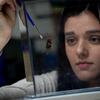 Biology student in a lab examining a spider and holding a brush