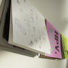 Handmade books hang sideways on a string against a white wall.