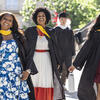 Three students wearing graduation gowns and smiling at the 2025 Commencement ceremony