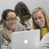 Students collaborating in front of a laptop in class