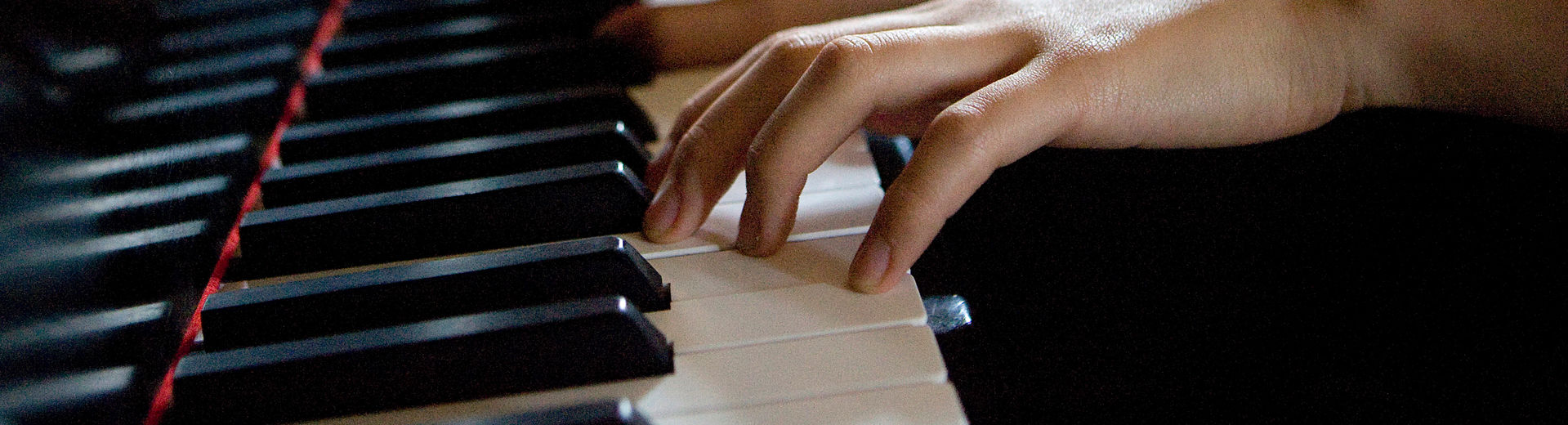 Six hands on piano keys playing a song