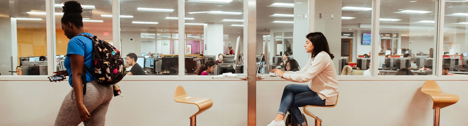 A College of Liberal Arts student studies at a table in front of a computer lab.