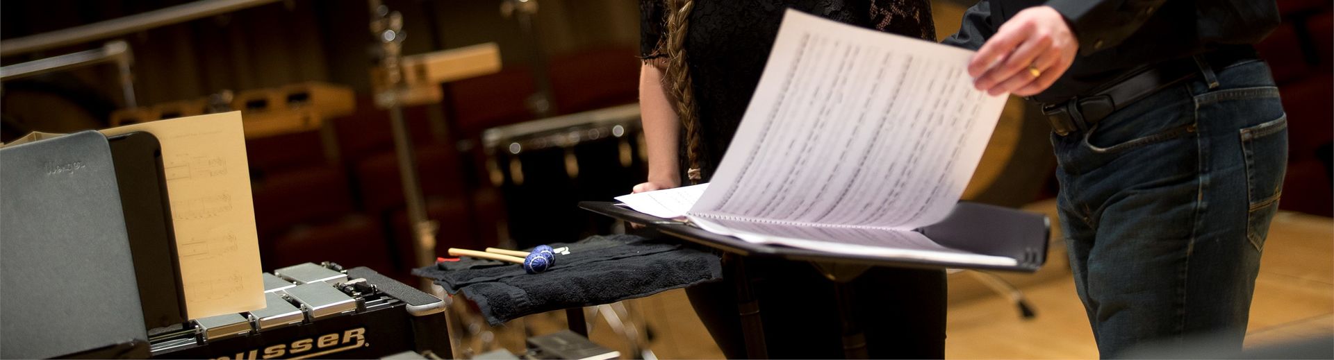 A student and professor look at sheet music together.