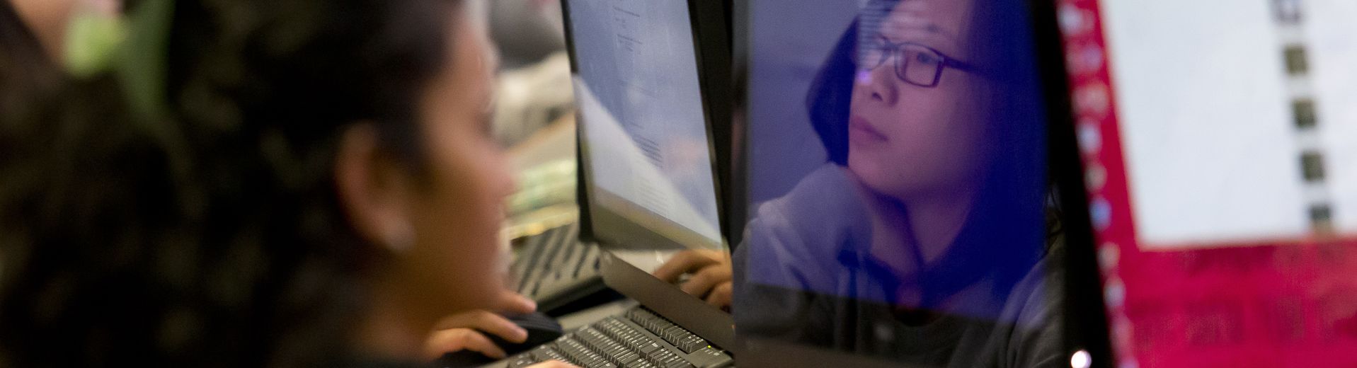 A student's face reflected in a computer screen.