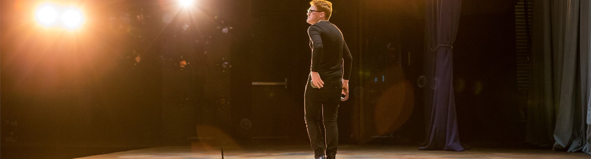 An actor standing on stage under spotlights.