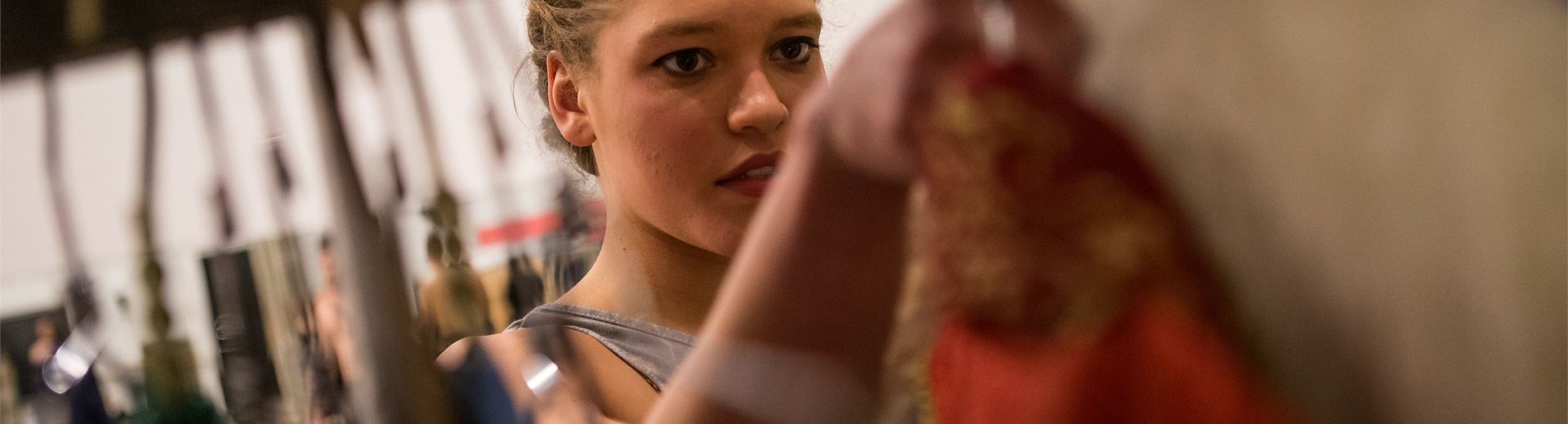 An actress selects a costume off of a rack.