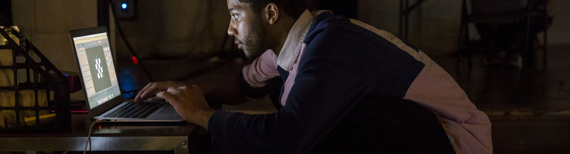 Student looking at a computer screen in a dark room.