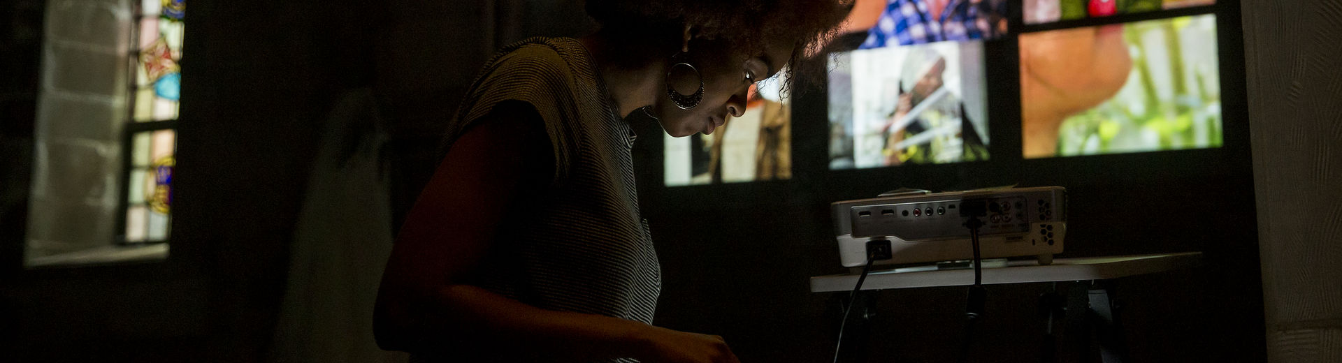 Woman looking at a screen with projected images behind her on a wall.