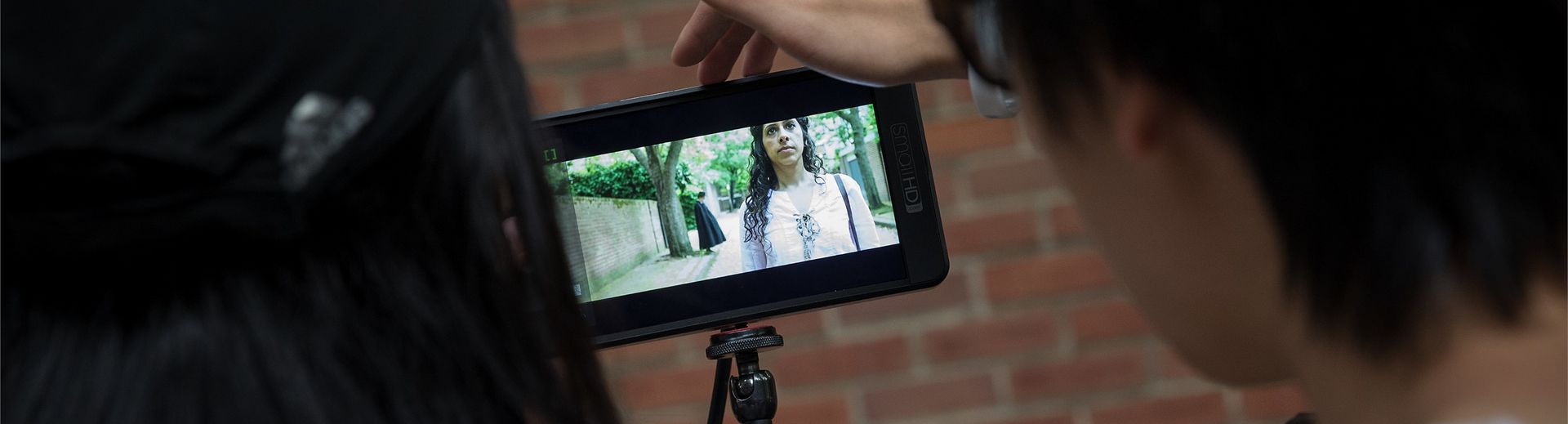 Students watch the shooting of a film on a small monitor.