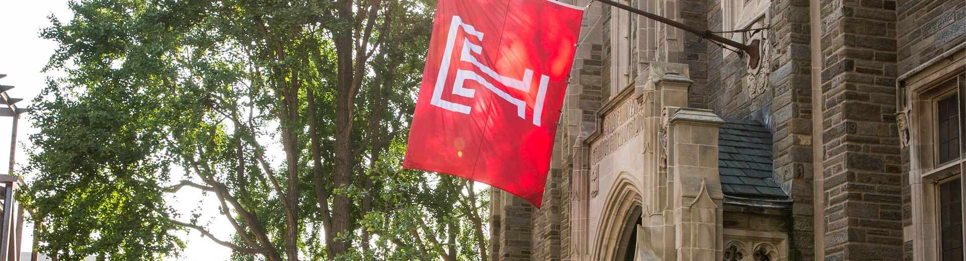 Temple University flag hangs from a historic building on campus.