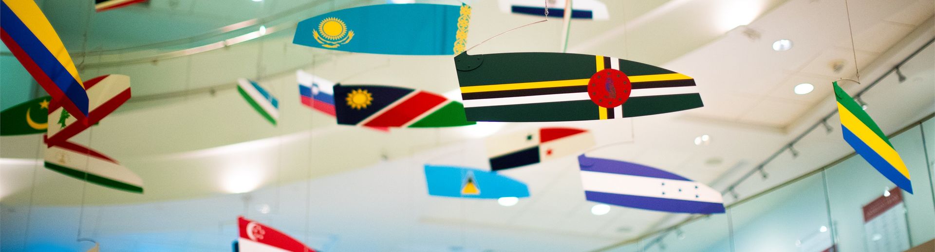 Colorful international flags hanging from ceiling in a business school lobby