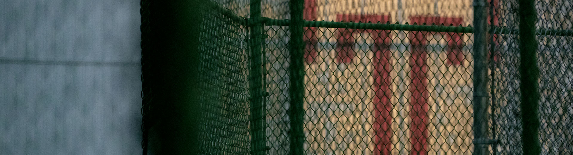 The red Temple T painted on a white background behind a chain link fence