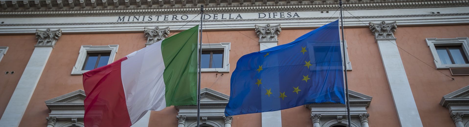 The Italian flag waves in front of a historic building in Rome.