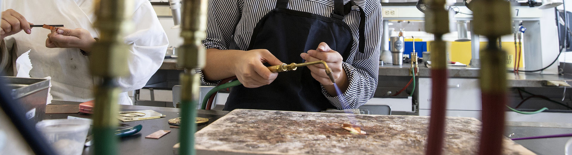 A student wearing safety glasses is working with a torch in Tyler's Metals studio.