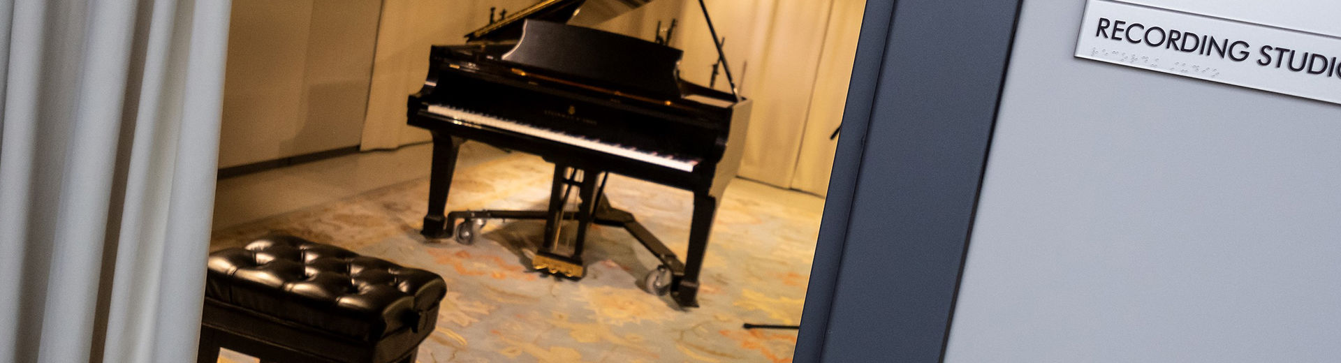 Practice room in music school with a grand piano and blue patterned carpet