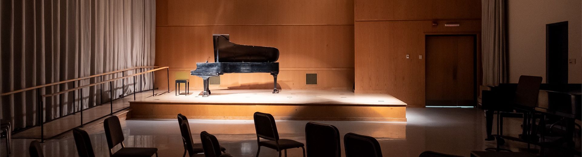 A piano sits on a stage with low lighting.