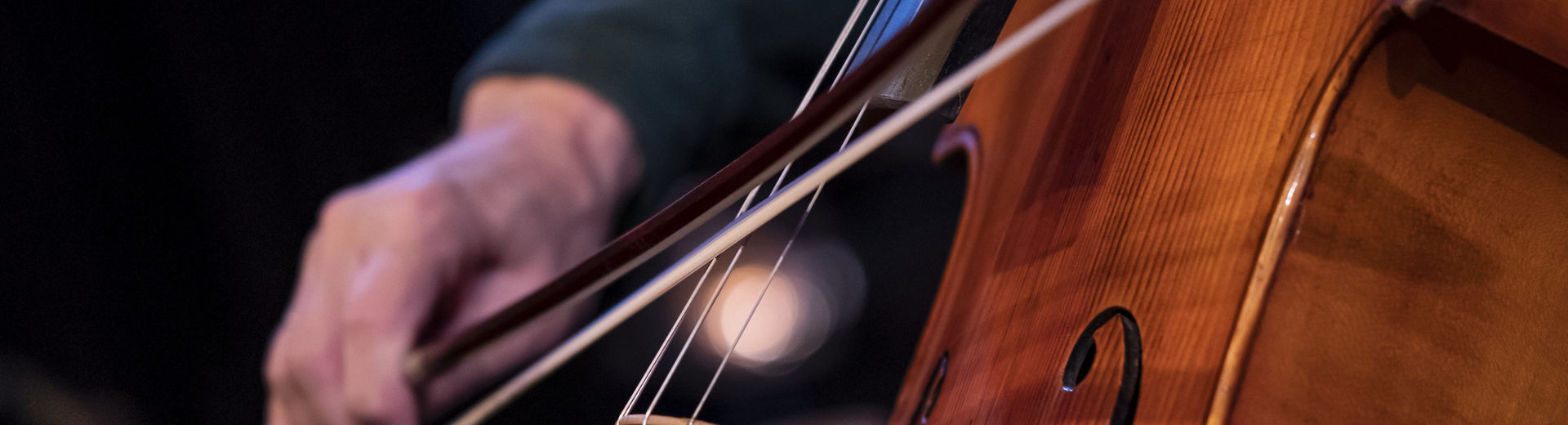 Close up image of a student playing the cello in a performance.