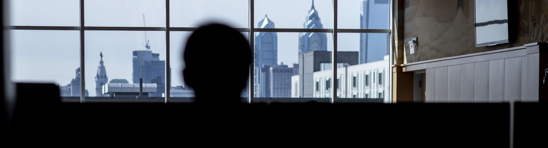 A student looks at the Philadelphia skyline through the windows of a building at Temple University.