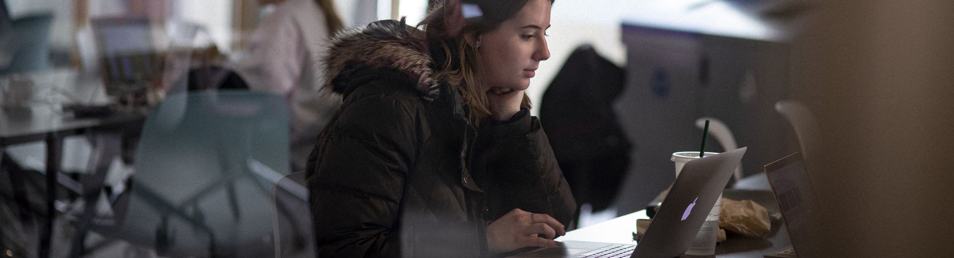 A girl sitting in front a computer doing school work. 