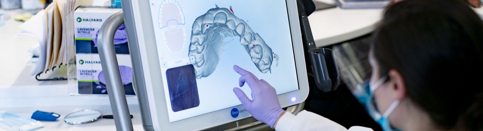 Dental student examines teeth film from computer.