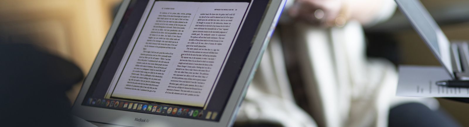 Laptops with screens full of text documents are seen in a classroom setting.