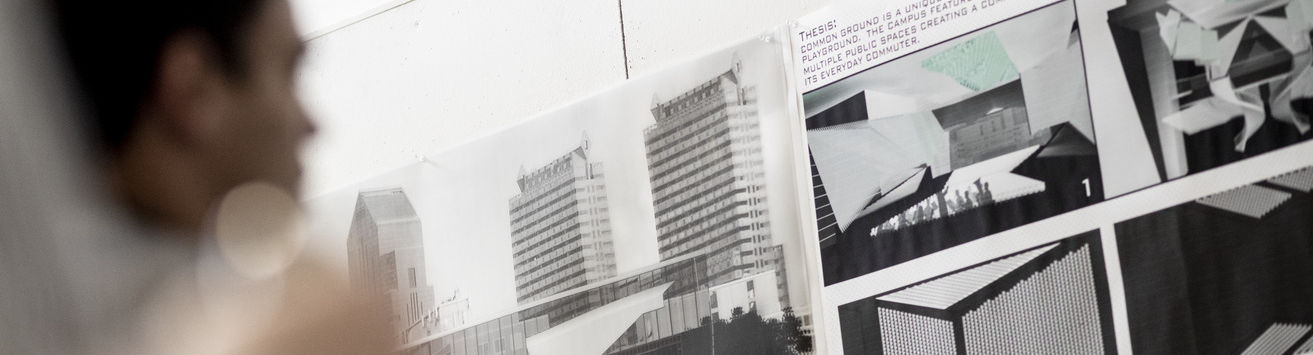 Black and white architectural renderings appear on a wall as a blurred figure looks on.