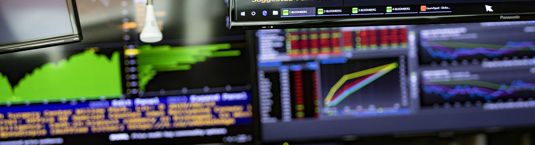 Multiple computer screens displaying financial analysis information in charts and graphs