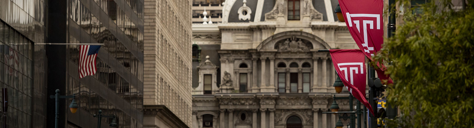 Philadelphia's City Hall building on Market Street lined with cherry red Temple T flags