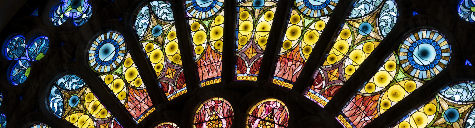 The interior of a stained glass window with blue, green, yellow and red glass.