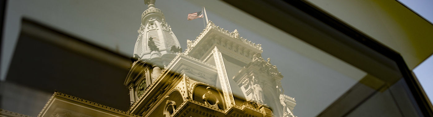Philadelphia City Hall is seen through a window.