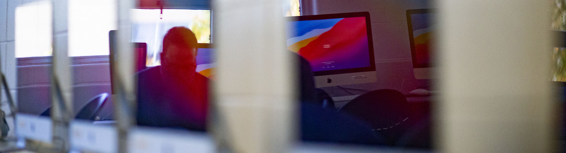 shot of Mac desktop computers lined up on a table.