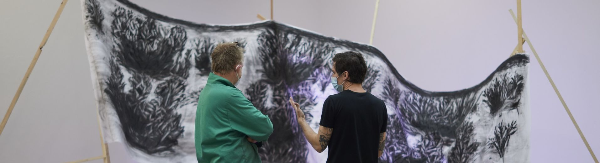 A professor and a student stand in front of a large, wide, black and white rectangular sculpture.