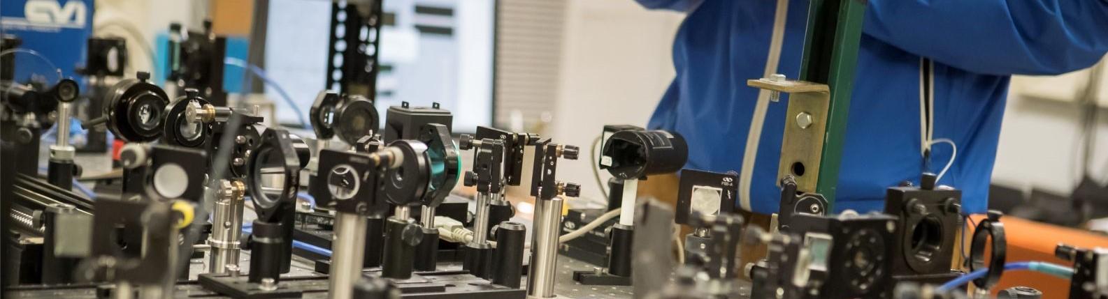 Temple student standing over table of equipment in a College of Science and Technology facility.