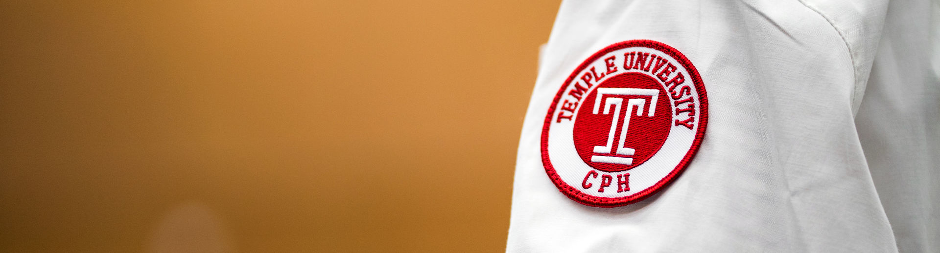 A close up of a student's white coat with the CPH crest on the arm