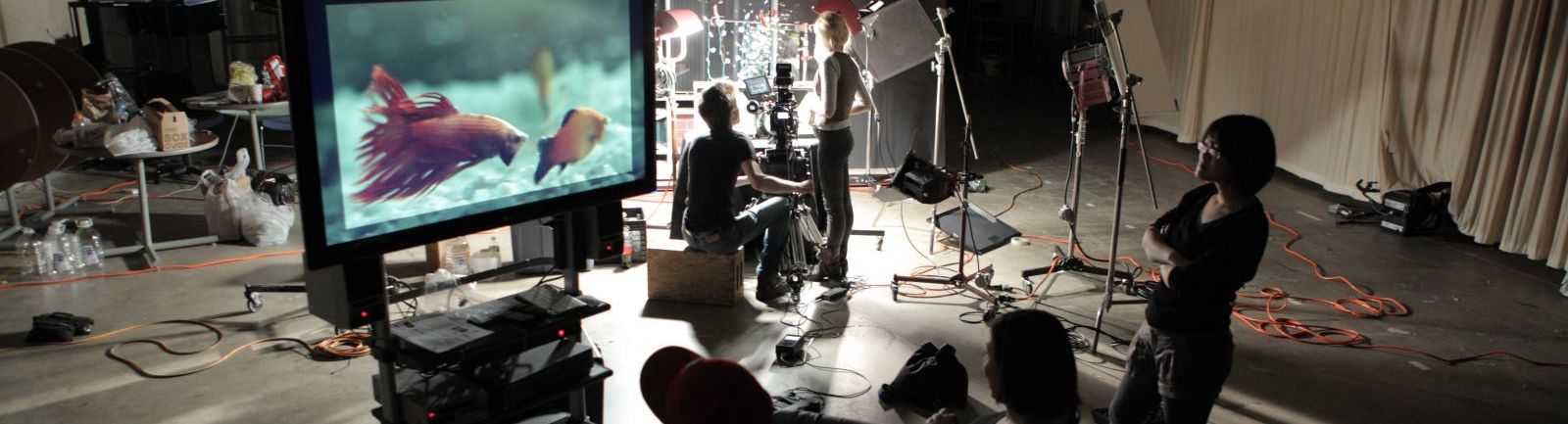 Students on a film set watch a large screen.