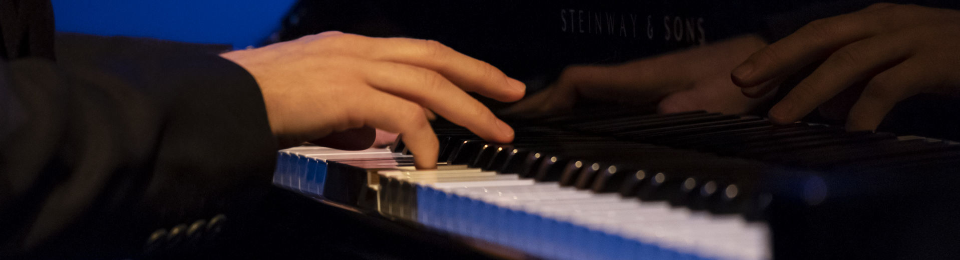 Hands playing a piano. 