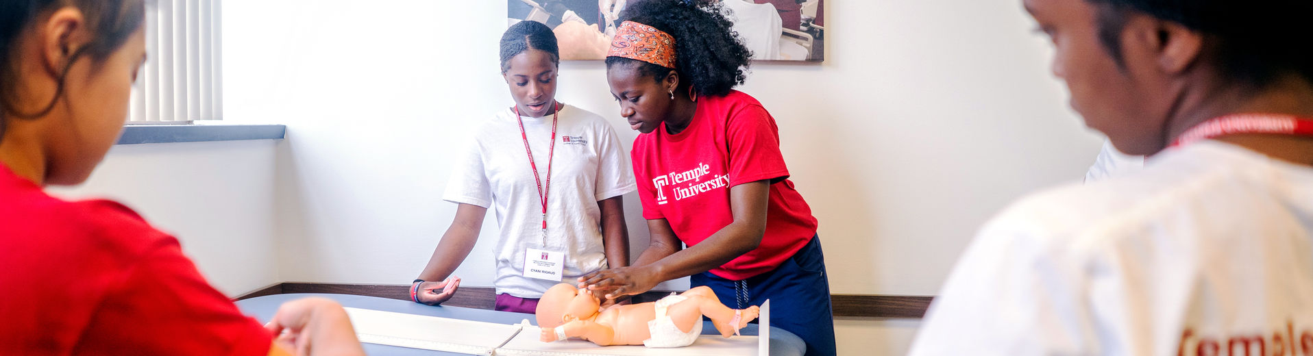 Two nursing students working with a simulated infant patient in the lab